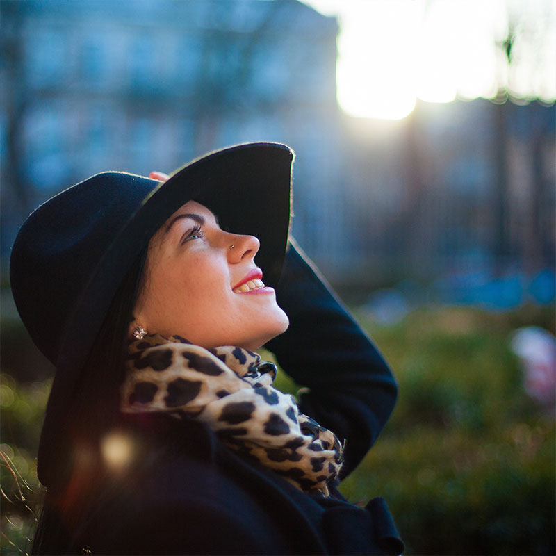 Foto de una mujer con un sombrero mirando hacia el ciel sonriendo